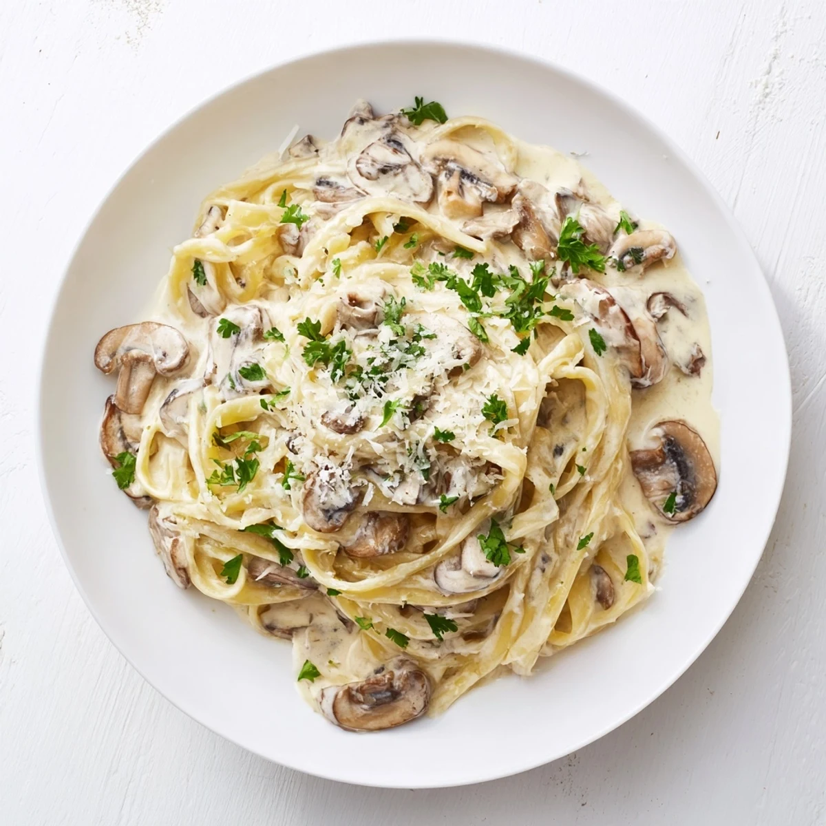 Steaming bowl of homemade creamy mushroom Alfredo pasta, featuring glossy sauce clinging to noodles, served alongside a glass of white wine for a complete dinner.