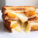 Mozzarella Stick Grilled Cheese is served warm with marinara sauce for dipping on a rustic plate.