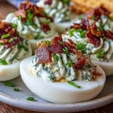 Spicy jalapeño popper deviled eggs with creamy cheese and crispy bacon on a white platter.  