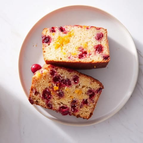A slice of moist cranberry and orange bread, with visible cranberries nestled inside the tender crumb.