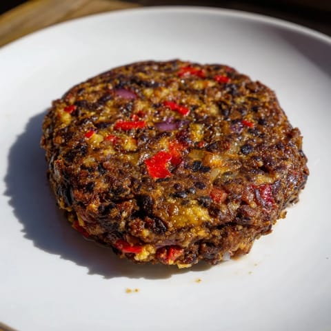 Golden-brown, homemade black bean burgers sizzling in a pan, full of savory spices.