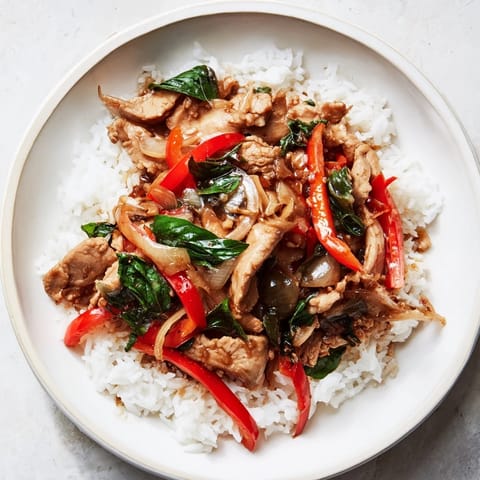 A sizzling close-up showcases vibrant ingredients in these delicious Thai Basil Chicken Bowls.