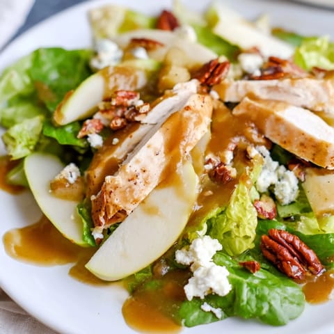 Freshly tossed Caramel Apple Chicken Salad with vibrant greens, juicy apple wedges, dried cranberries, and crumbled feta, drizzled with caramel-pecan dressing.