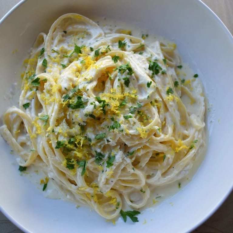 Tangled strands of Lemon-Garlic Greek Yogurt Pasta, coated in a luscious, bright sauce, garnished with parsley.