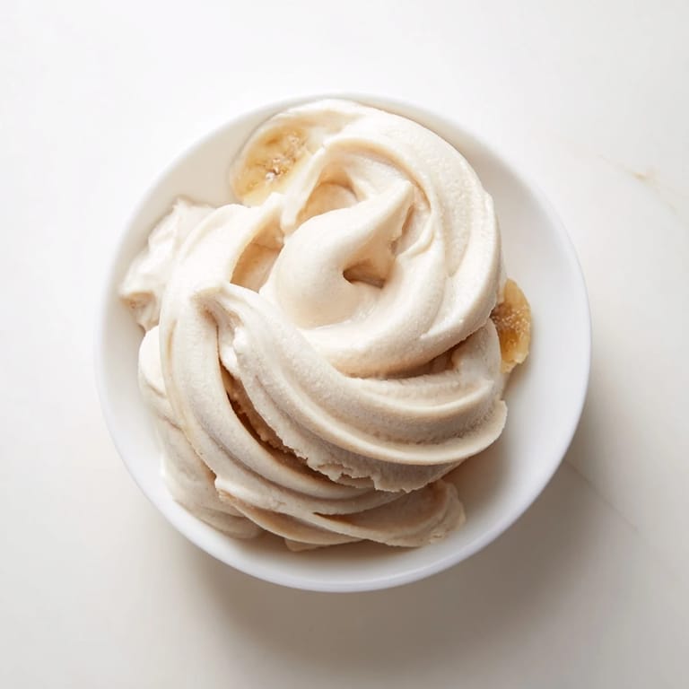 This vibrant bowl of 2-Ingredient Banana Ice Cream looks smooth, with a perfect, soft-serve texture.