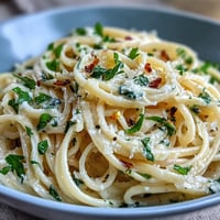 Creamy lemon butter pasta with fresh garlic and Parmesan, served in a white bowl with a sprinkle of parsley.