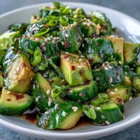 Vibrant smashed cucumber and avocado salad with toasted sesame seeds, a fresh side.